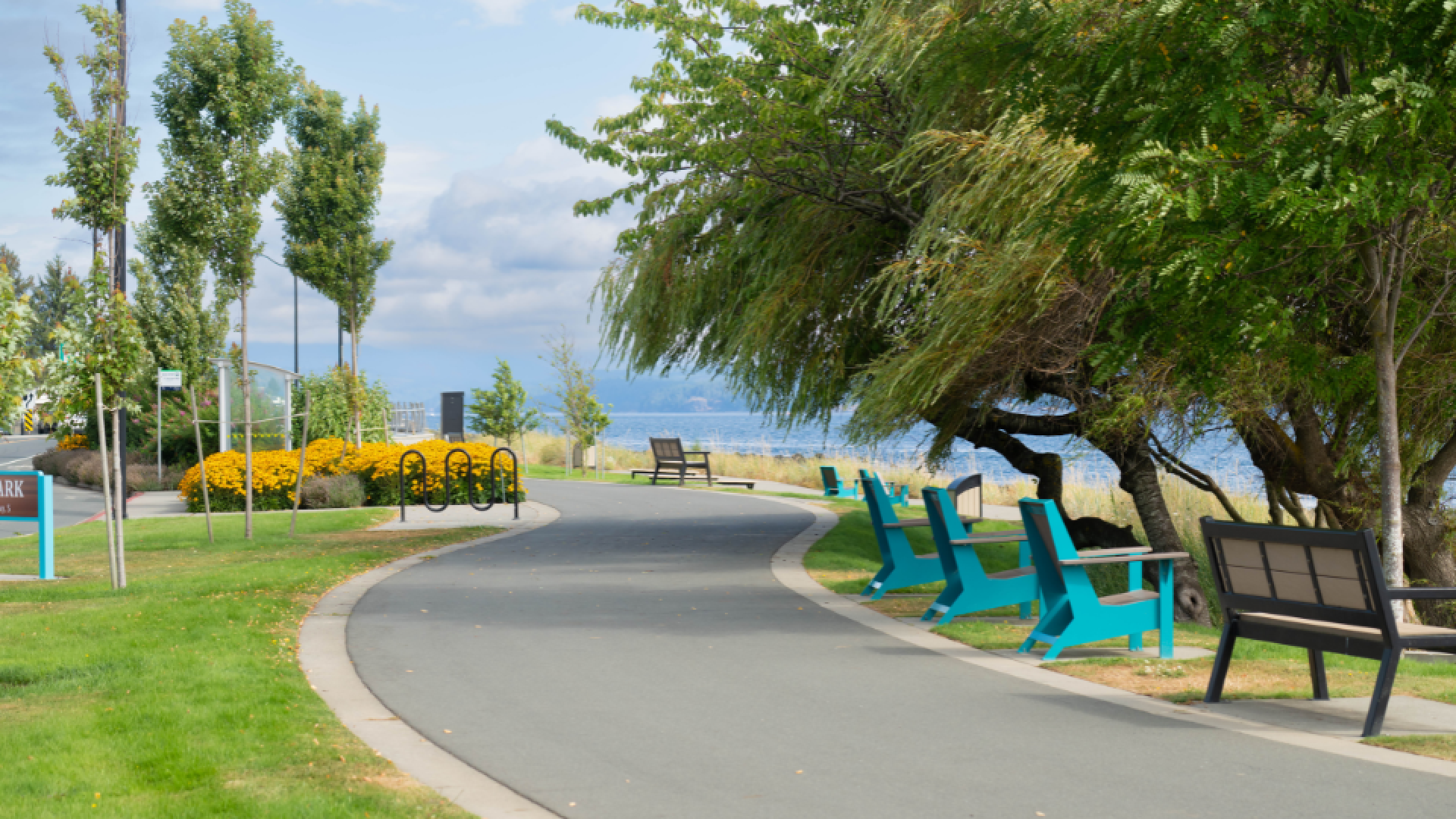 Walking and bike path along the ocean with benches and chairs facing the ocean.