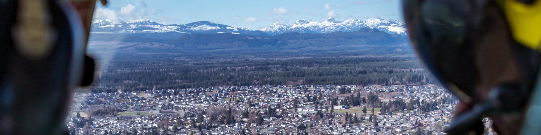 Aerial view of Campbell River with ocean coastline and surrounding forested mountains.