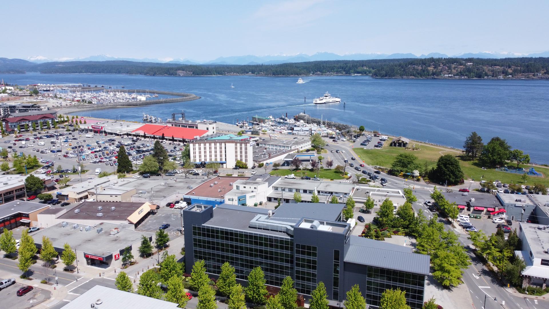 Aerial view of a coastal town with buildings, trees, and a harbour.