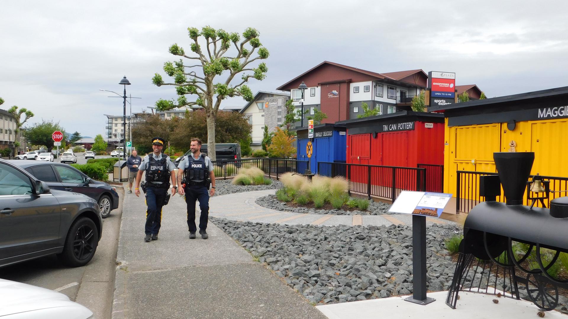 Two RCMP officers walking in front of the Rail Yard Market