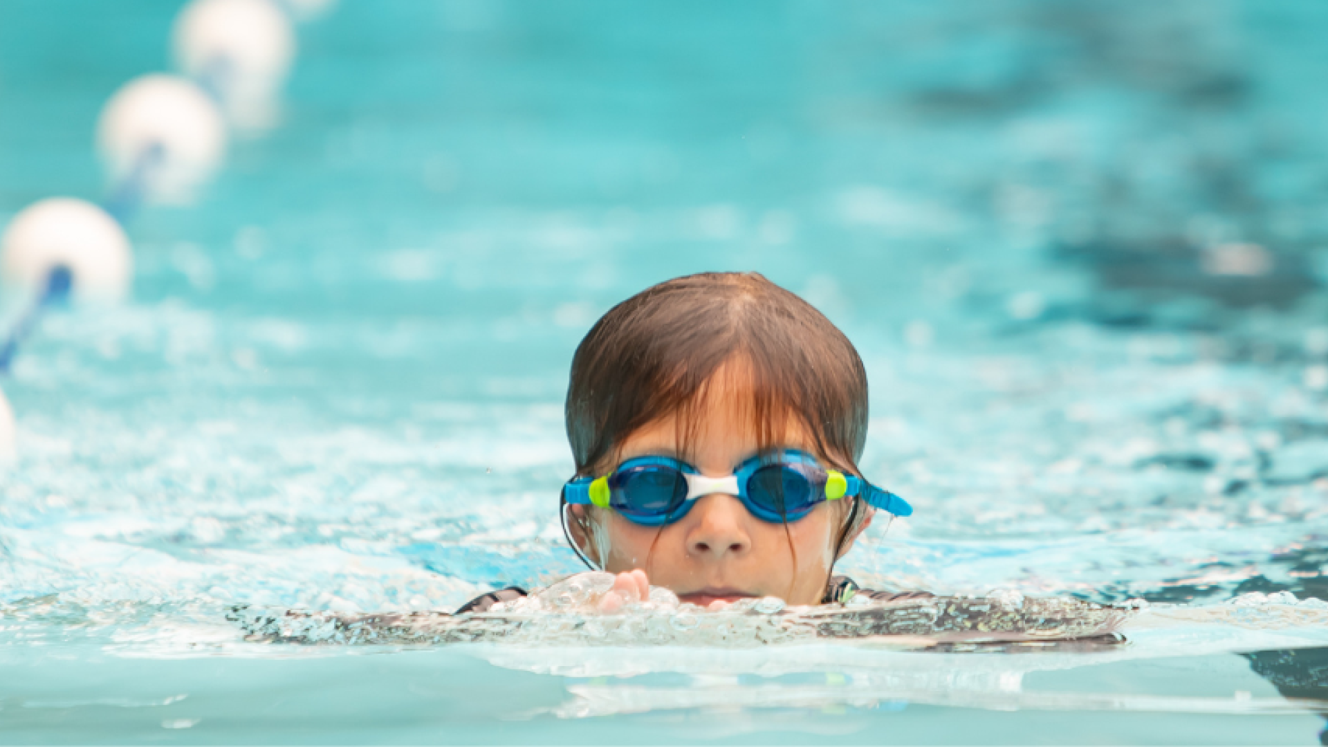 Child doing laps in a pool wearing goggles