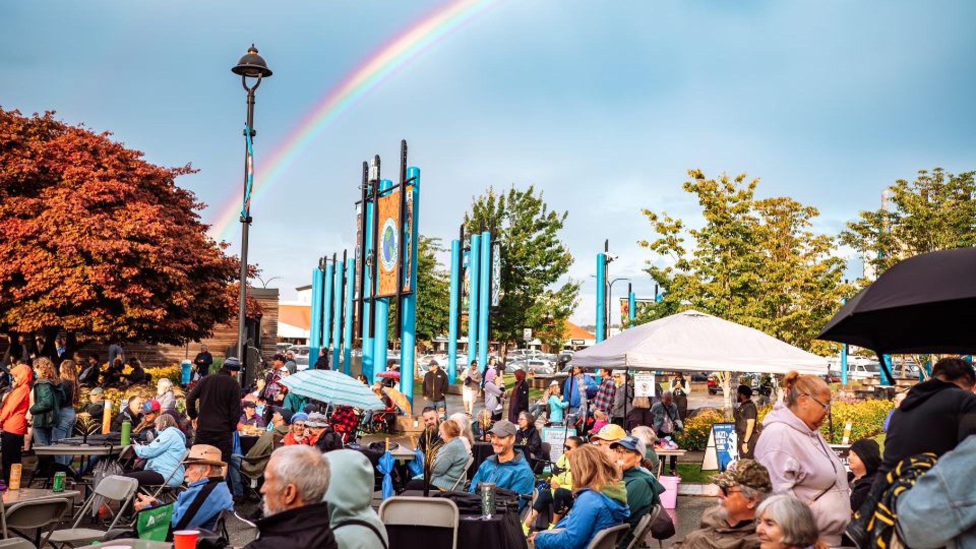 People gathered at CR Live Streets, smiling and enjoying the event with a rainbow visible in the background.
