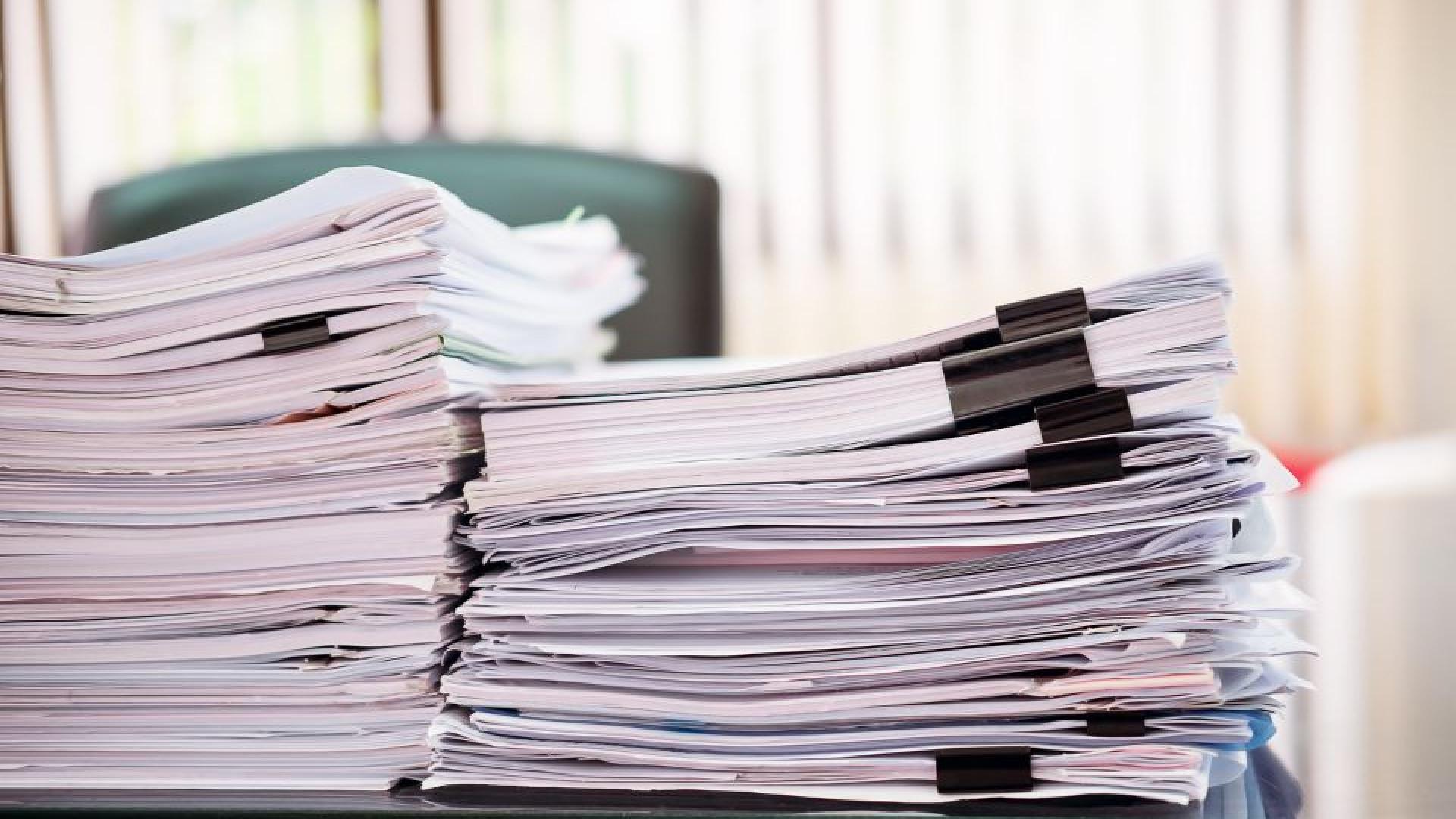 Stack of printed reports and documents spread out on a desk.