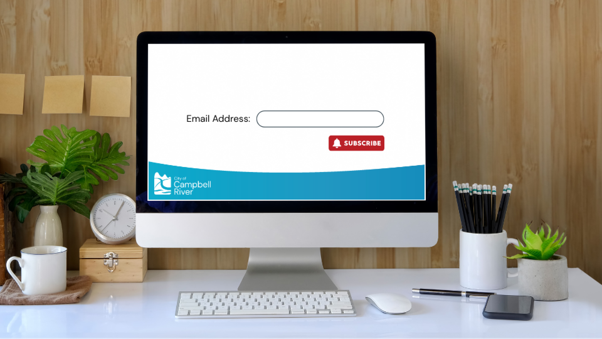 Computer desk with screen showing an email address text box and subscribe button.