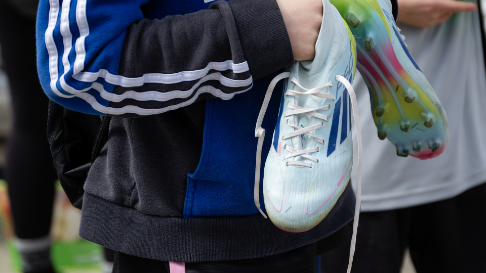 Soccer player holding soccer cleats.