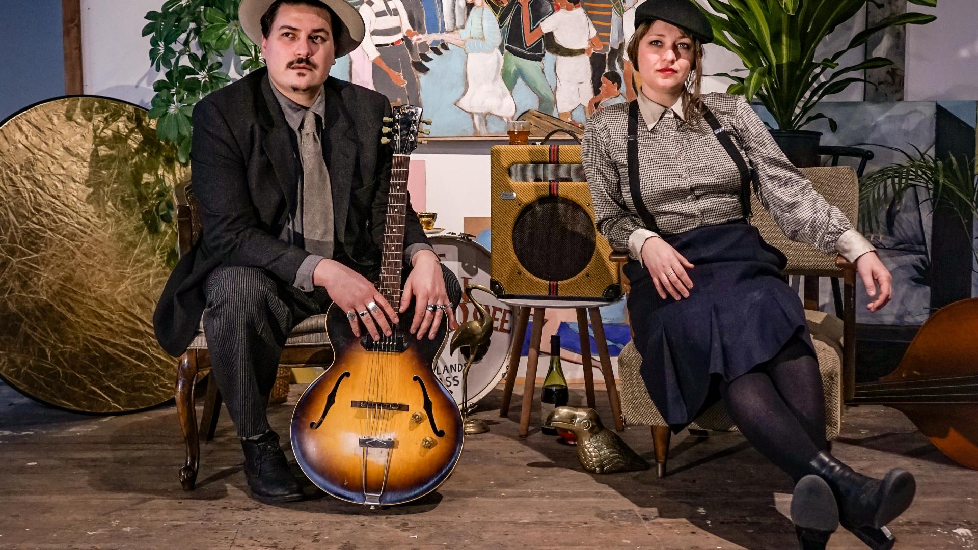 The two members of the band Blue Moon Marquee seated at a table with instruments arranged around them. The photo was provided courtesy of the band.