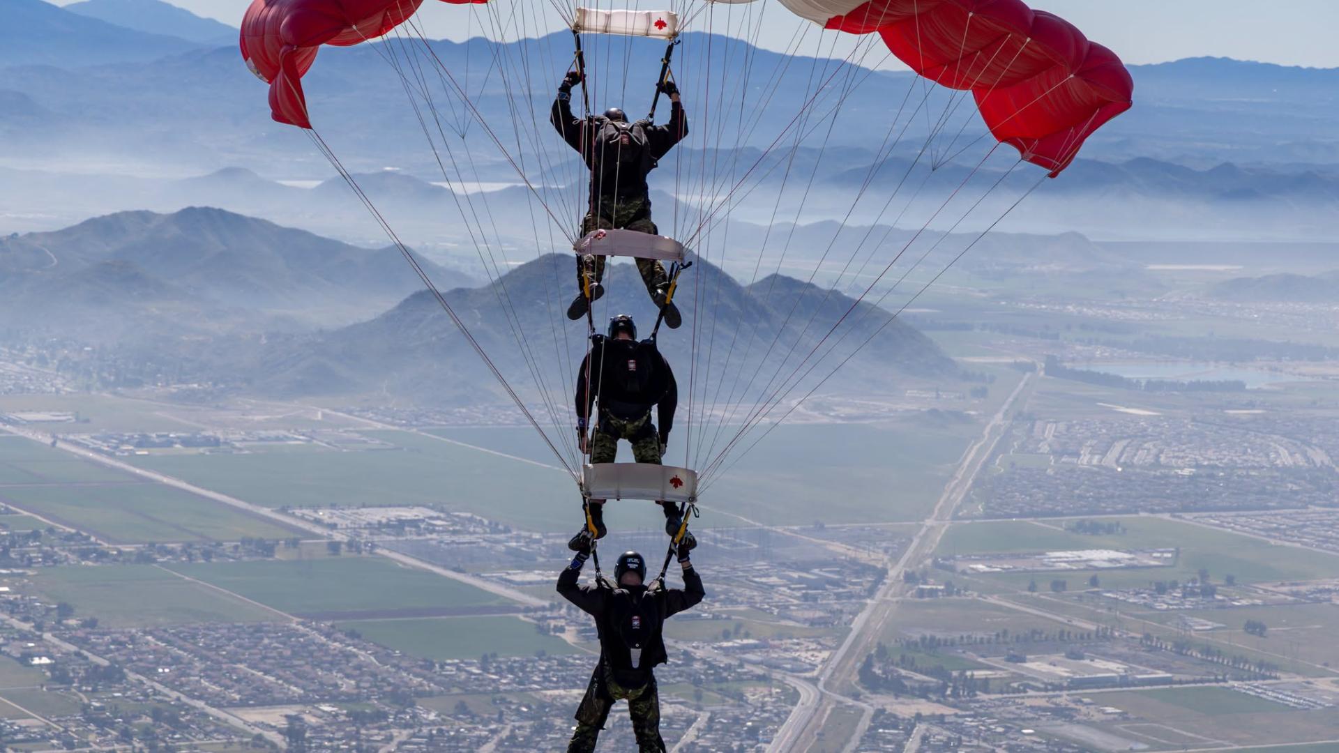 Three Skyhawk divers parachuting down to earth.