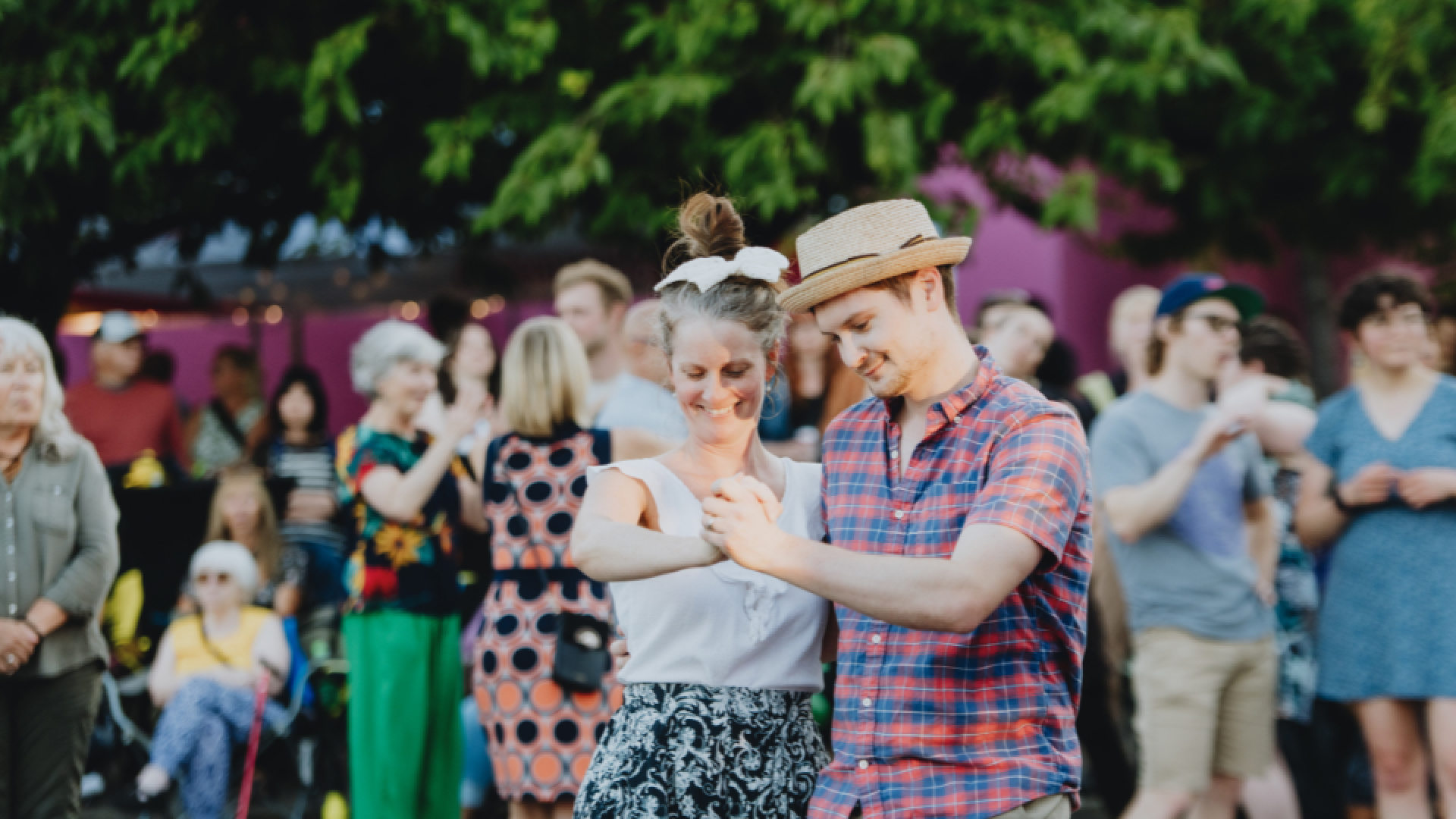 Two people swing dance in Spirit Square with a crowd of people in the background.