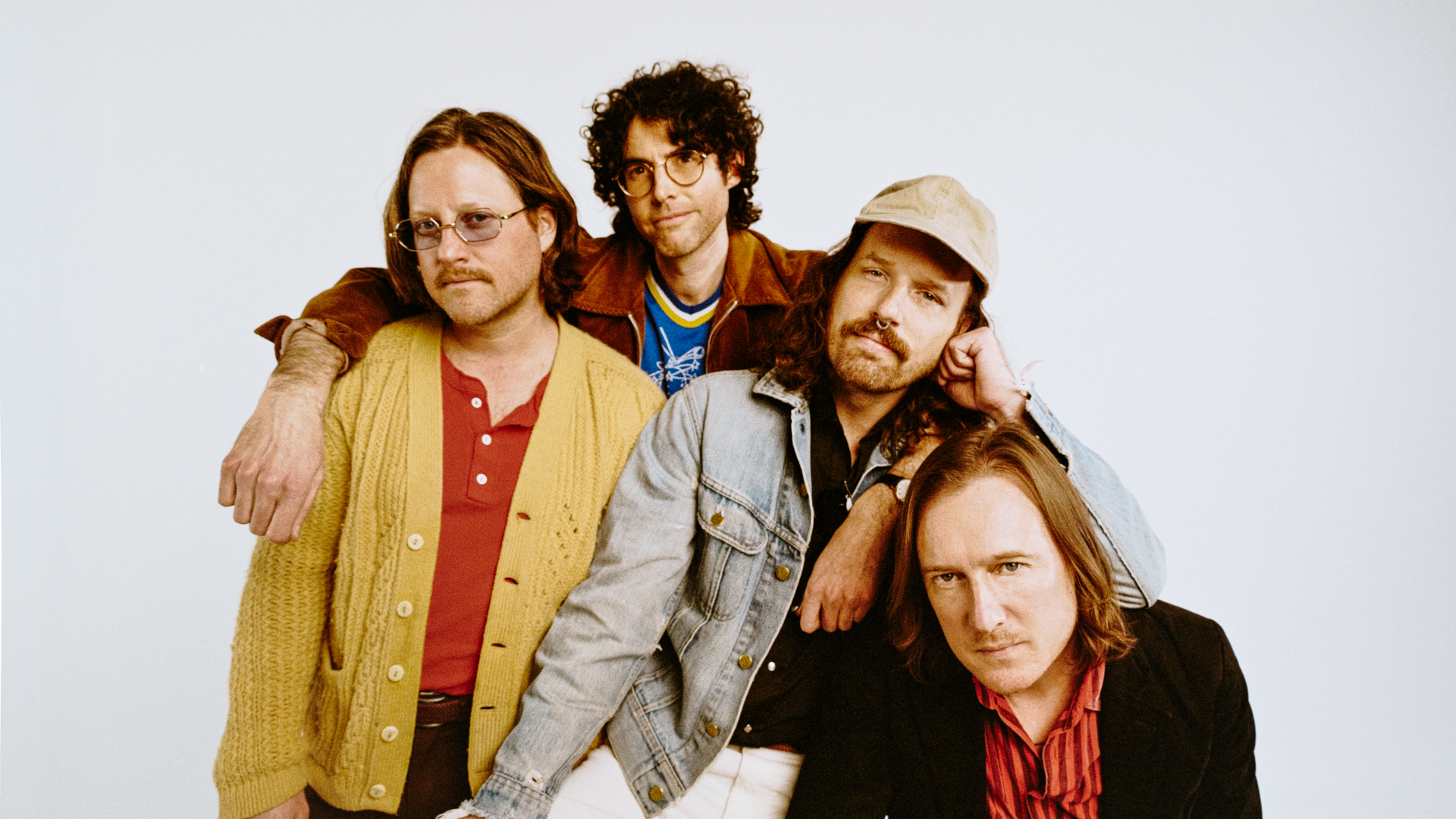 Yukon Blonde, a band of 4 members huddle together and pose for the camera.