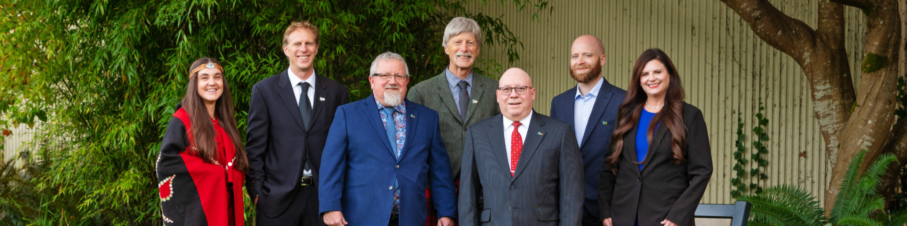 The Mayor and six councilors stand in a row smiling outside of City Hall.