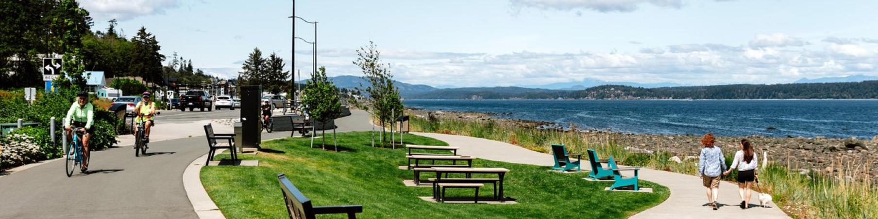 Two cyclists on a path by the seawalk; two people walking near the ocean.