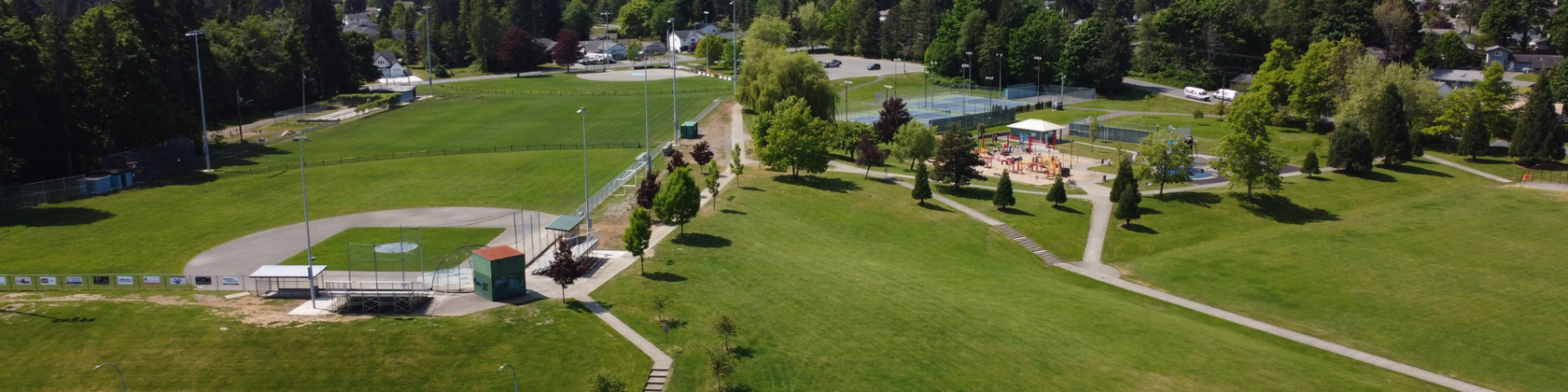 Aerial view of a baseball field surrounded by other playing fields with green grass and trees.