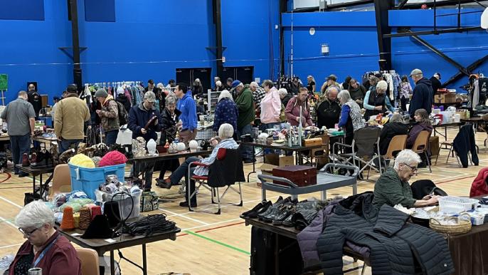 Various people at booths inside the Sportsplex offering help to repair different items.
