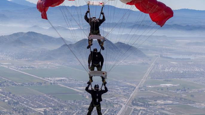 Three Skyhawk divers parachuting down to earth.