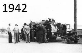 Group of men inspecting a vintage fire engine, black and white photo.