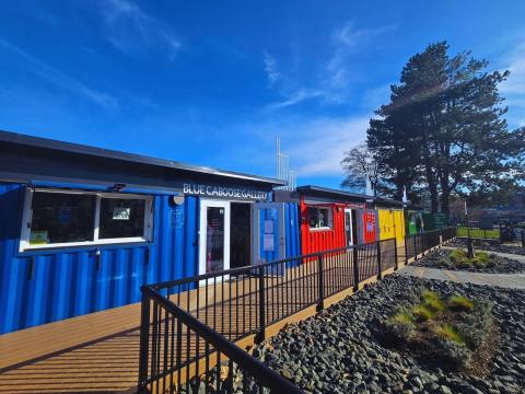 The Rail Yard Market with various vendors under a blue sky and a tree stands tall in the background.