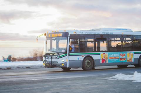 BC Transit bus driving along the ocean with a driver in passengers.