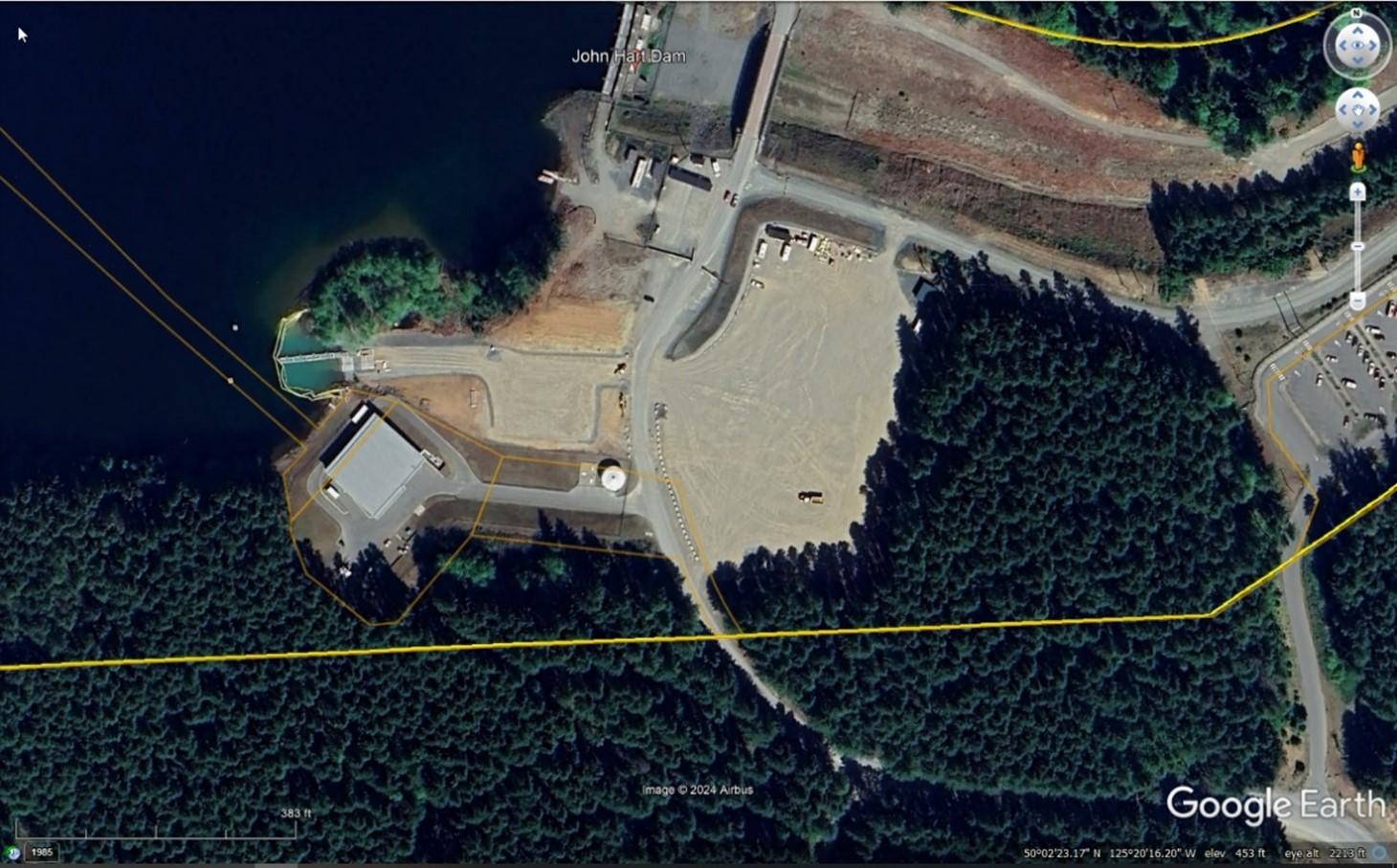 Aerial view of a lake with a dock, surrounded by forest and roads.