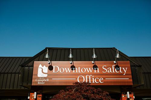 Four light sconces point down on the sign above the Downtown Safety Office sign.