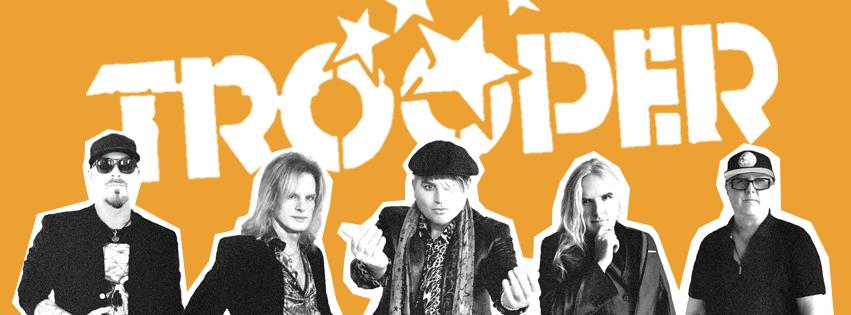 Five members of the band Trooper pose together against a yellow background. Text overlay reads "Trooper". Star graphics overlap the text.
