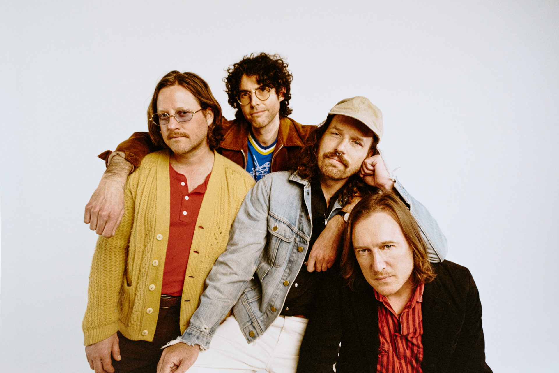 Yukon Blonde, a band of 4 members huddle together and pose for the camera.
